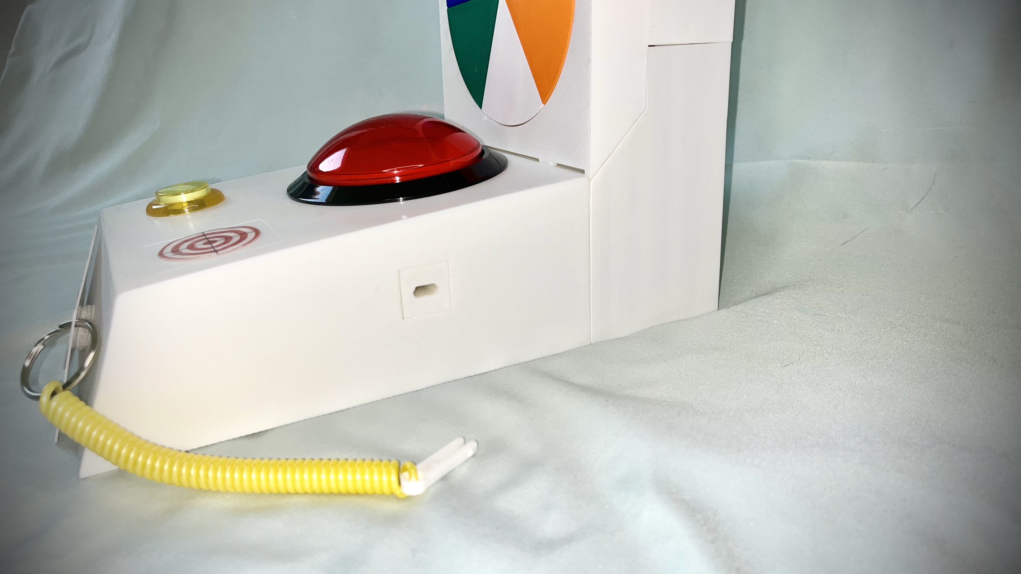 Close-up of Neuro Stim controls — large red dome button, gold sensory button, coiled oral motor element, and PECs communication cards